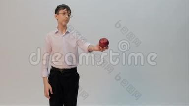 一个戴眼镜的年轻人提出要吃一个红苹果。 一个穿着白色衬衫的滑稽学生脸上流露出悲伤的情绪